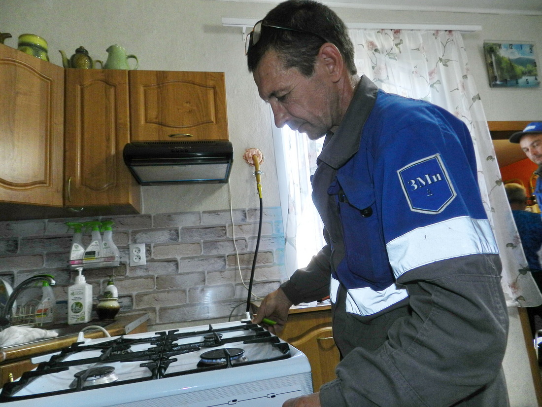 Газовик проверяет работу плиты в доме абонента