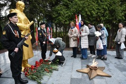 Жители поселка возлагают цветы к мемориалу с Вечным огнем